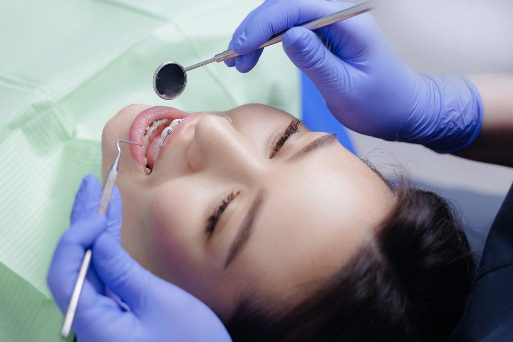 Top view Caucasian female receiving orthodontic treatment with braces at dental clinic.