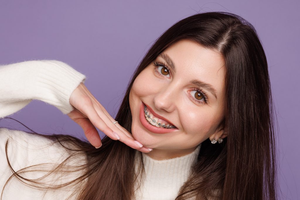 Young woman smiling, she seems happy with braces with her hand under her chin