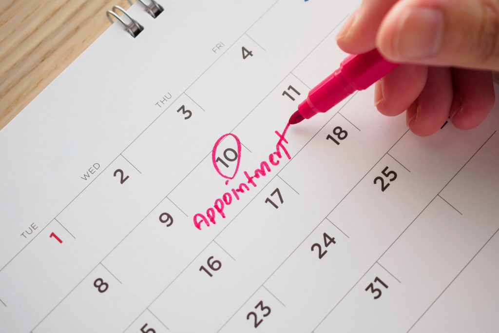 Hand with pen writing on calendar date appointment concept