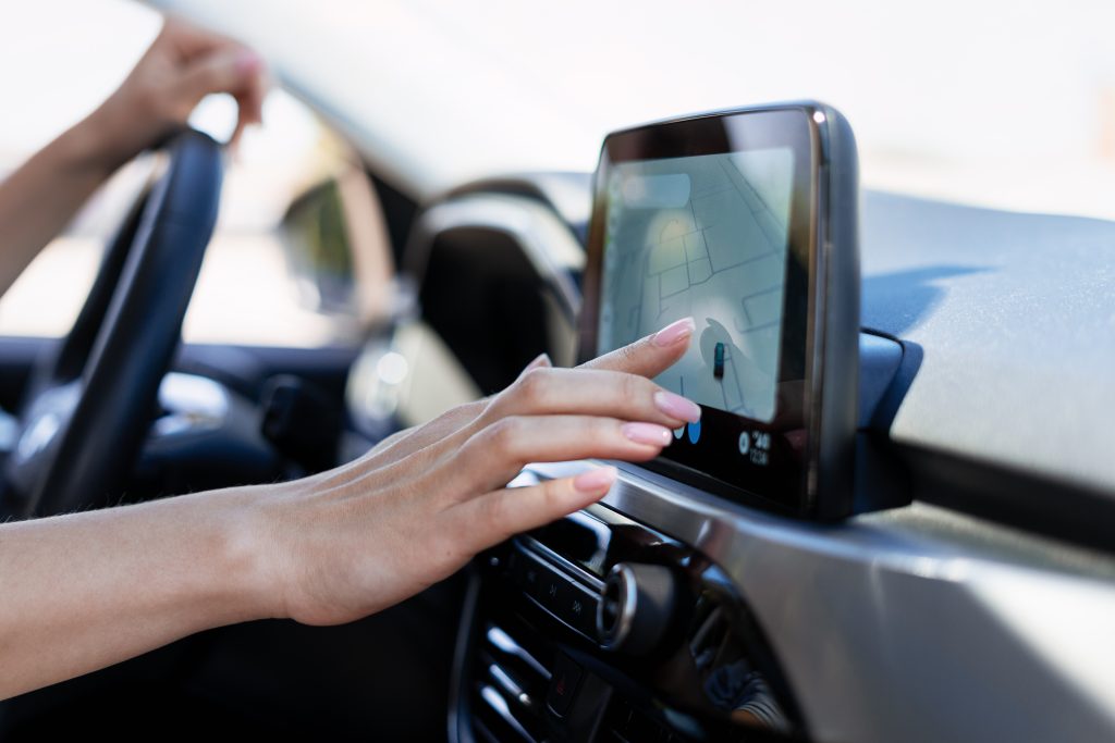 Woman interacting with a car's dashboard touchscreen navigation system while driving, effortlessly managing directions and routes