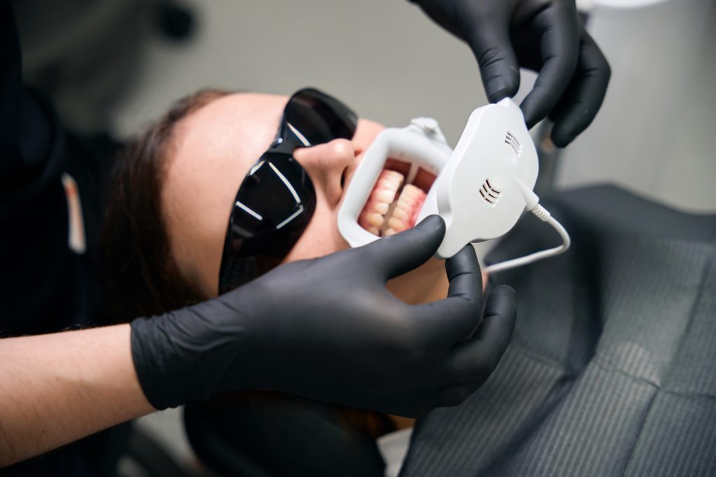 Caucasian woman receiving teeth whitening in dental clinic